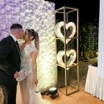 Bride and groom kissing against a flower backdrop in the photobooth