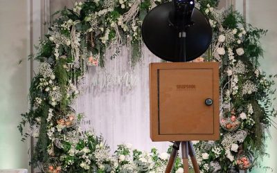 A custom flower arch being used as a backdrop with a vintage photo booth