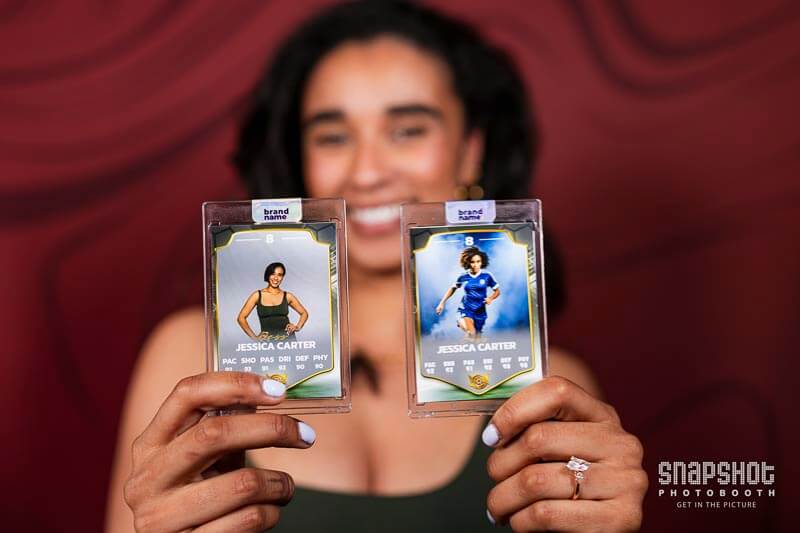 a woman holding up a customized trading card from a photo booth