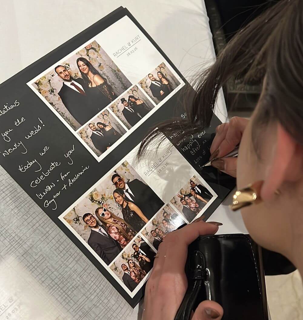 Arrigo-wedding-guest-book. A woman putting her postcard and signing the guest album.