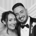 A beautiful shot of the bride and groom posing happily together in front of a white fabric photo booth backdrop at their luxury Phoenicia Hotel Malta wedding.
