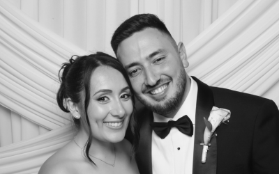 Jessica & David -Hero A beautiful shot of the bride and groom posing happily together in front of a white fabric photo booth backdrop at their luxury Phoenicia Hotel Malta wedding.