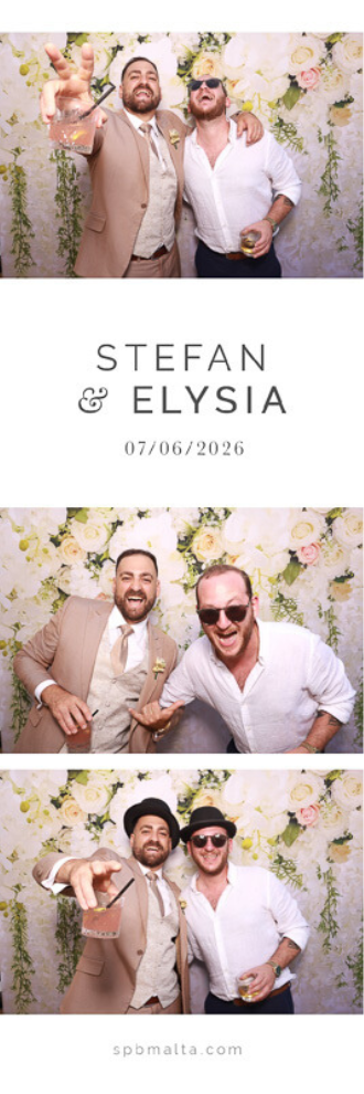 Stefan & Elysia-04 The groom Stefan and a friend wearing hats and sunglasses posing in front of a white and pink floral backdrop.