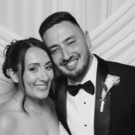 A beautiful shot of the bride and groom posing happily together in front of a white fabric photo booth backdrop at their luxury Phoenicia Hotel Malta wedding.