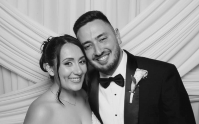 jessica-and-david-wedding-hero-image A beautiful shot of the bride and groom posing happily together in front of a white fabric photo booth backdrop at their luxury Phoenicia Hotel Malta wedding.