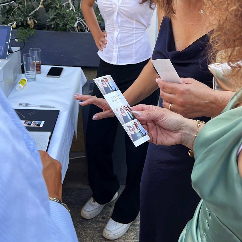 valletta-waterfront-wedding-venue-photo-strip Wedding guests holding a custom photo booth strip from a celebration at a Valletta waterfront wedding venue.
