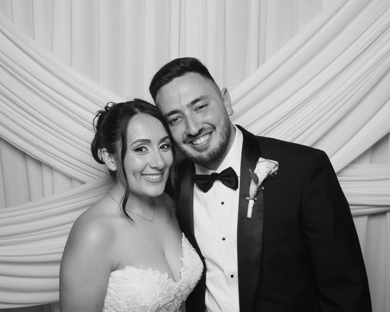 wedding-photo-booth-malta-bride-and-groom-smiling-together. Smiling bride and groom posing together in front of a white fabric photo booth backdrop at their Phoenicia Hotel Malta wedding celebration.