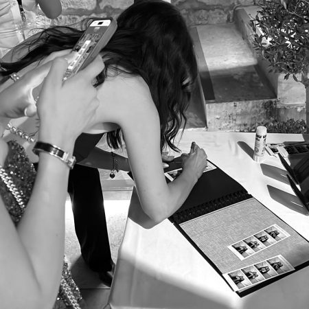 wedding-photo-booth-malta-guest-book-with-photo-strips A wedding guest signing a custom guest photo album next to black and white photo strips during the Phoenicia Hotel Malta wedding reception.