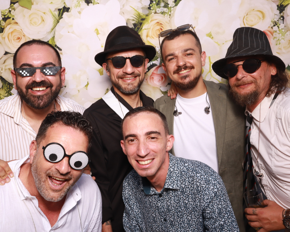 friends-taking-photo-together-at-wedding-photo-booth Group of friends smiling and taking a memorable photo during a wedding celebration.