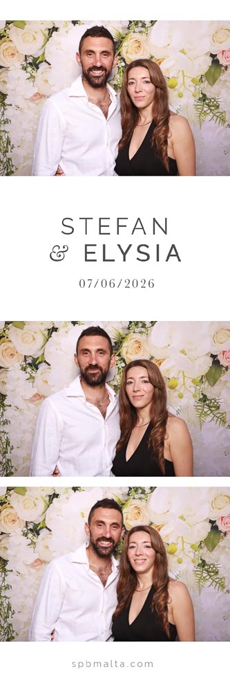 wedding-photo-booth-malta-couple-photo-strip-5 A man in a white shirt and a woman in a black dress posing together in front of a white and pink floral wedding backdrop.