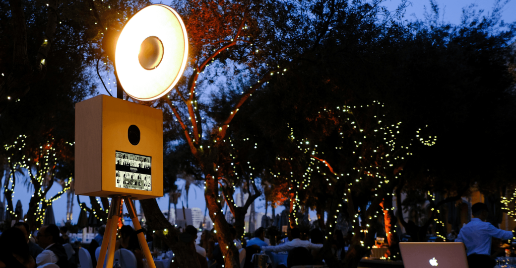 Wedding Photo Booth at an Outdoor Reception in Malta Vintage photo booth at an outdoor wedding reception in Malta, beneath trees wrapped in fairy lights at dusk.